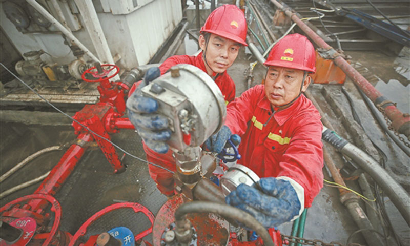 距离大庆油田3000多公里的川渝油气增储上产主战场——大庆油田2万多平方公里的流转区块所在地，一年四季云雾缭绕、山路崎岖、靠山临崖，井架藏身于大山深处，小井场中进行着大规模压裂作业。图为钻井队副司钻牵头检查封隔器压力表。