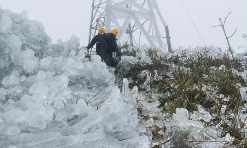 积冰堵塞了本就陡峻的山路，车辆无法通行，突击队员徒步穿过晶莹的“冰山”，行走的黄色安全帽在高高的山顶格外耀眼。