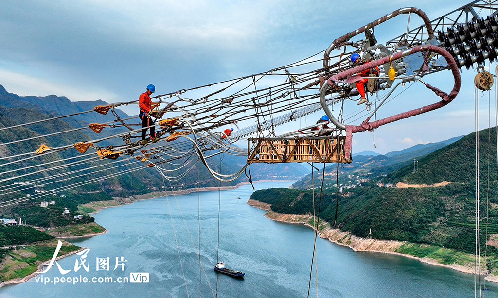 2022年8月20日，湖北省恩施土家族苗族自治州巴东县东瀼口镇绿竹筏村，电力工人冒着40℃以上的高温跨越长江施工作业。张远明 摄