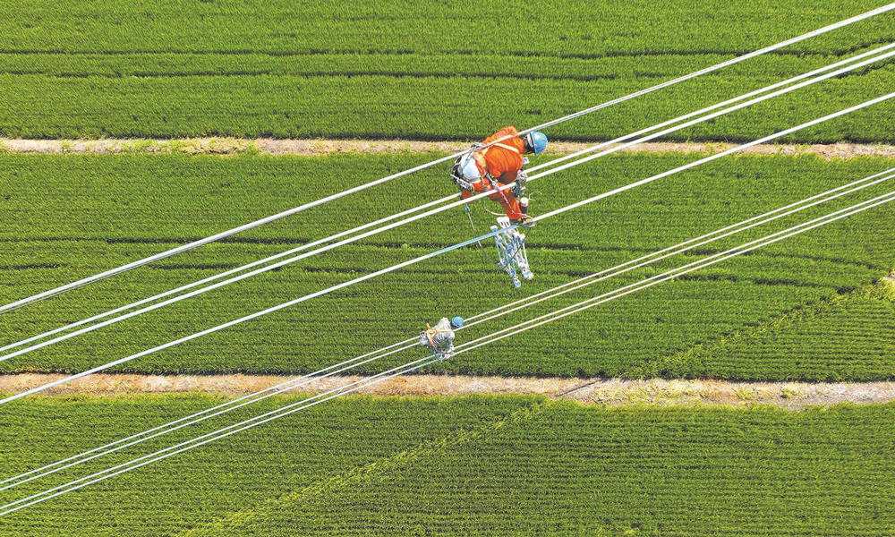 近日，国家电网各单位强化电网运行控制，加强设备运维管理，落细负荷管理措施，成功应对高温、台风、洪涝灾害，保障电力可靠供应。图为8月23日，国家电网江苏送变电公司施工人员在±200千伏扬州—镇江直流输电线路工程现场架设导线。该工程是我国首个“交流改直流”输电工程，投运后可增强江苏电网过江输电通道的送电能力，将苏北的绿色电力送至苏南地区。
