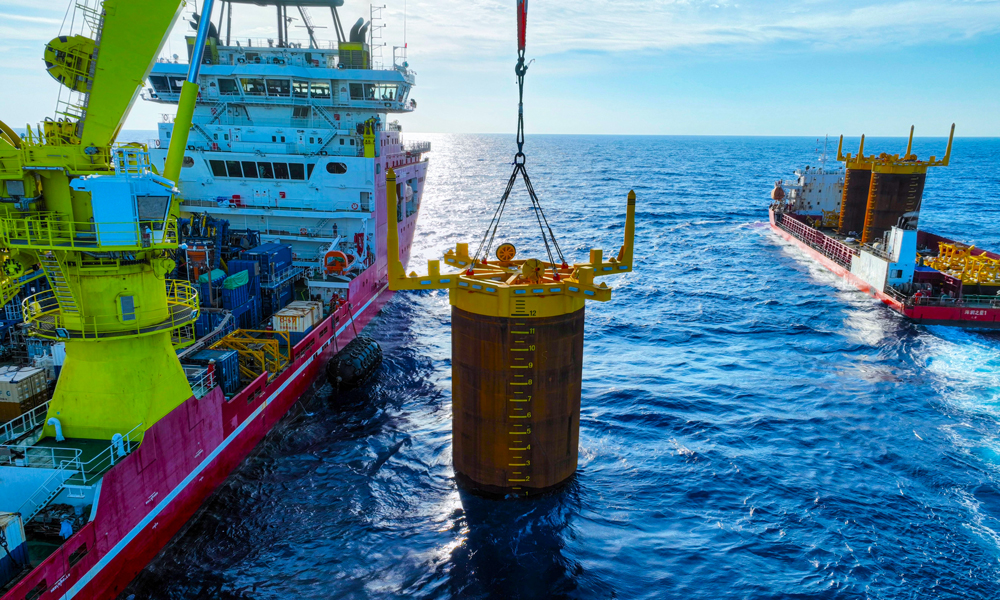 项目部根据吸力桩重心位置量身定制3套吊装索具，确保起吊时桩体垂直于海平面。现场强化定位精度控制，布控6个定位信标，形成“六边形”定位阵校准方阵。投入两台ROV（水下机器人），采用“阻尼艏向调整法”进行艏向细微调整，保证艏向精度。贯入作业中，船舶吊机和ROV协同作业，精准控制钩头载荷和贯入压力，确保吸力桩缓慢平稳沉降。最终实现了3套吸力桩一次性高精度贯入成功。图为吸力桩安装作业现场。