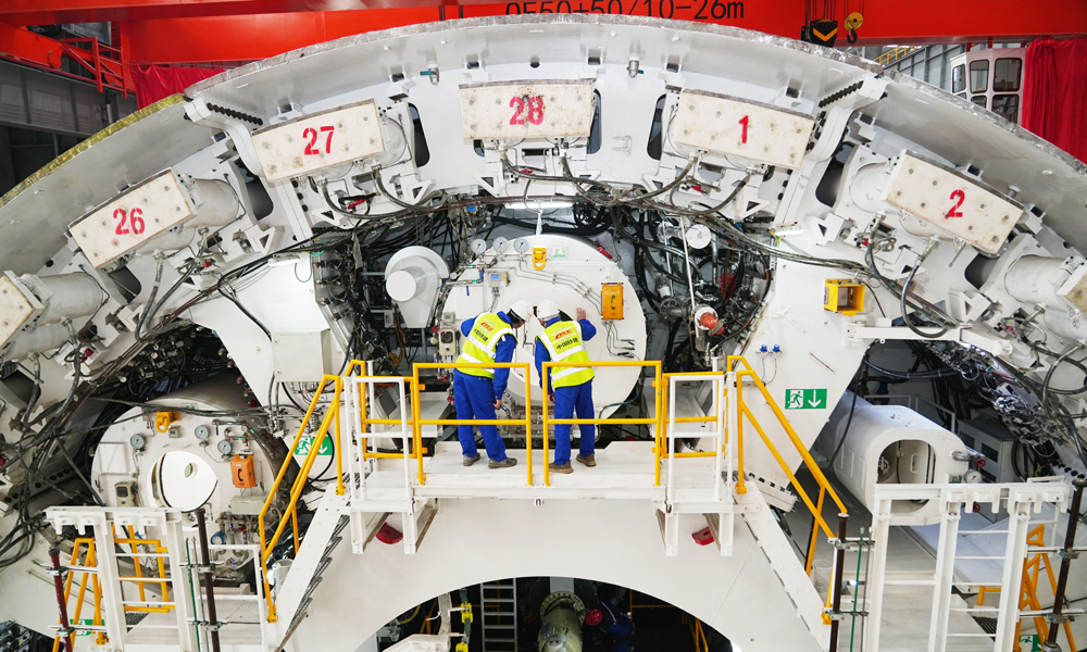 面对项目施工风险和难点，中铁十四局项目团队不断创新攻关，通过增加刀具数量，加密刀具旋转轨迹，配备高硬度、高韧性滚刀，以提高刀盘整体切削性能，同时配备刀盘刀具磨损自动监测功能、主驱动状态监测系统、气垫式泥水压力平衡系统、同步双液注浆系统等，对盾构机运行状态进行连续监控，实现切口压力的精准控制，保证及时调整机身姿态和同步注浆参数，实现盾构隧道沉降的毫米级精控。图为技术人员在验收盾构机。