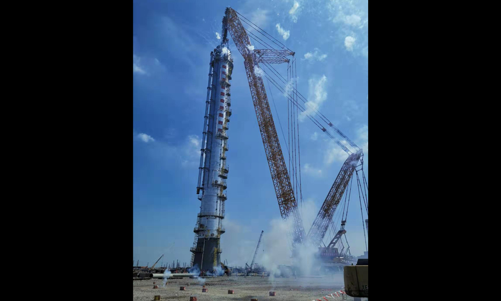 本次吊装的1#丙烯塔精馏塔，直径7.5米，高102.22米，本体重量1260吨，吊装重量1500余吨，就位半径30.4米。施工难度大，安全标准高。中国化学工程精准作业，顺利完成二期3#乙烯项目首个千吨级塔器吊装。图为吊装现场。