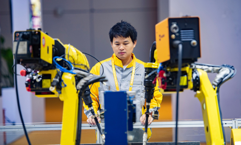 图为11月5日，在第二届进博会装备展区，工作人员在沪工国际（香港）有限公司展台前查看点焊机器人设备运行情况。（新华社记者 普布扎西 摄）